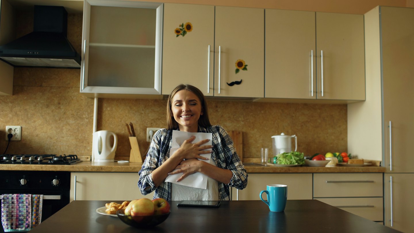 Woman holding a stack of papers in a modern kitchen.