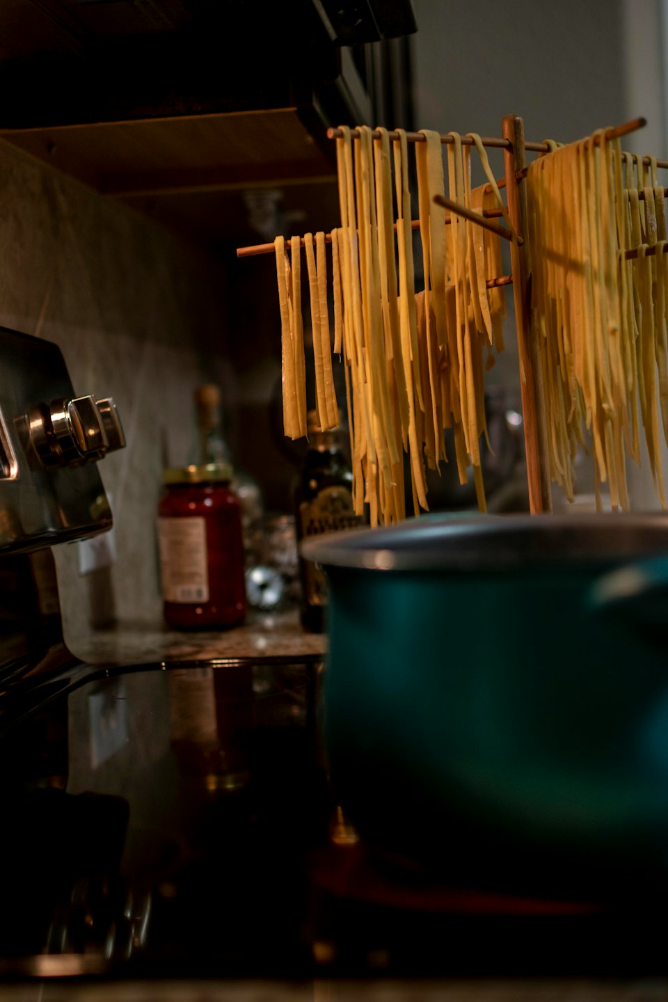 Fresh pasta strands hang to dry on a wooden rack.